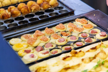 Making takoyaki balls filled on a hot pan snacks and local street food in japan festival.