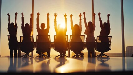 Group of People in Office Celebrate Success and Achievement with Raised Arms, Silhouetted Against Sunset Through Large Windows, Conveying Teamwork and Celebration in Silhouette of People at Sunset