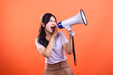 Woman holding megaphone shouting loud isolated on an orange background