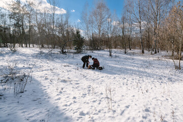Two people in a snowy winter forest are trying to light a fire.