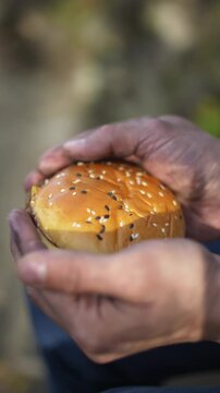 hamburger in dirty hands close up vertical video. unhealthy fodo concept. world food crisis, export, import. harvest problems in the world, increase in food prices