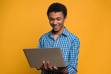 Happy Afro American teenager working with laptop.