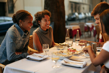 Friends enjoying dinner at an outdoor restaurant in Rome