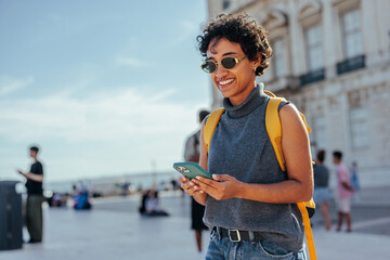 Smiling tourist using smart phone in lisbon, portugal, exploring commerce square