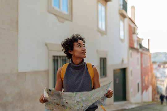 Tourist exploring lisbon using a map and looking around - Powered by Adobe