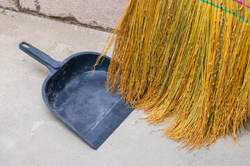 A broom along with a black scoop is lying on the ground now