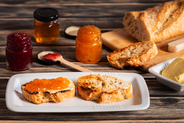Preparations for making toast with butter and peach and raspberry jam, along with all their ingredients, close-up.
