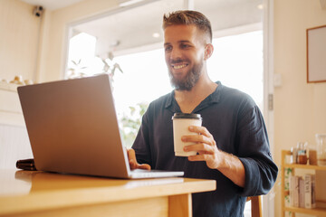 A man is working hard on his laptop in a cozy coffee shop, fostering productivity and creativity
