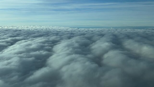 An aerial view through the pilot&rsquo;s eyes of a sea of clouds as seen from a jet airplane cokpit. Sunny day, blue sky. 4K
