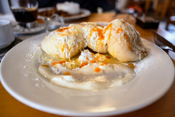 Yeast dumplings stuffed with apricot with curd and butter on plate.
