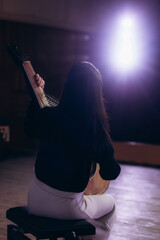 Musician Playing Traditional String Instrument in a Dimly Lit Artistic Scene