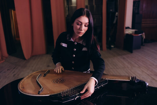 Woman Tuning A Traditional Musical Instrument in a Wooden Performance Hall