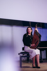 Fototapeta premium Young Musician Holding a Plucked String Instrument on Stage in Performance