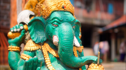 An old hindu stone statue of Ganesha covered with moss, standing on the str..