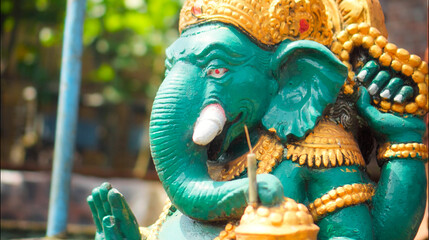 An old hindu stone statue of Ganesha covered with moss, standing on the str..