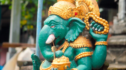 An old hindu stone statue of Ganesha covered with moss, standing on the str..