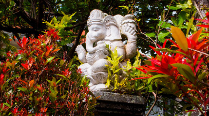 An old hindu stone statue of Ganesha covered with moss, standing on the str..