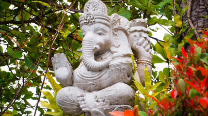 An old hindu stone statue of Ganesha covered with moss, standing on the str..