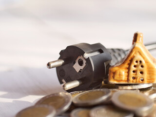 Borrowing money to buy a house. With a house, money and a power plug as elements. Business and...