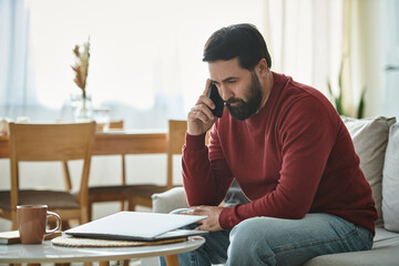 Elderly man deep in thought while on the phone in a cozy living room setting