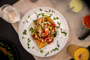 Delicious indian samosa garnished with fresh coriander, tomatoes and onions, served on a white plate