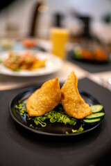 Delicious indian samosa garnished with fresh coriander, tomatoes and onions, served on a white plate