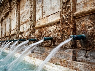 Row of water spouts in an old stone fountain