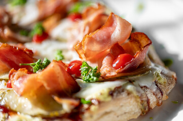 A close-up of a delicious sandwich topped with crispy bacon, fresh herbs, and a drizzle of sauce, capturing a tempting and appetizing moment for food lovers.