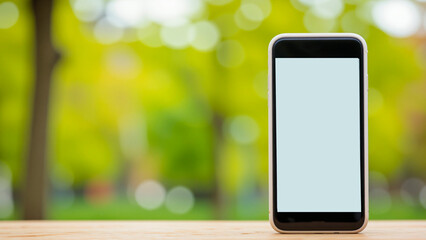 Smartphone on wooden table with blurred green background