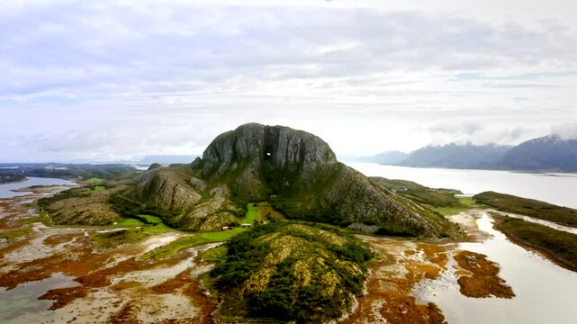 The drone soars high above Torghatten mountain, revealing its iconic hole and rugged form set against the stunning Norwegian landscape.
