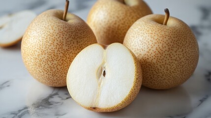 Fototapeta premium Three ripe Asian pears on marble, one cut in half. Perfect for healthy eating, recipes, or food blogs.