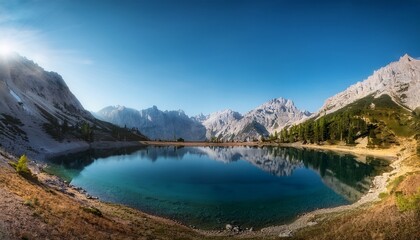 Obraz premium Serene mountain landscape with a calm lake and clear blue skies. 
