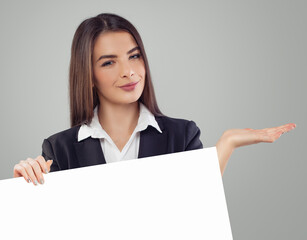 Fototapeta premium Beautiful positive business woman holding white empty paper banner background with copy space indoor