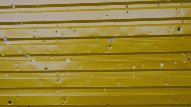 Metal profile fence riddled with shrapnel. Damage to metal fence as a result of artillery shelling. War in residential areas. Armed conflict in Ukraine.