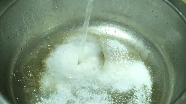 Cleaning kitchen metal sink from plaque and lime deposits using Sodium percarbonate powder, hot water and brush. Chemical reaction with release of steam and abundant foam.