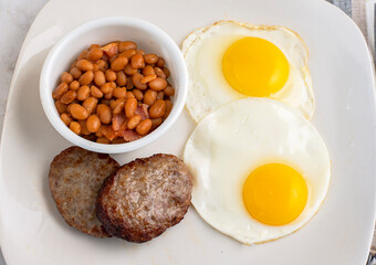 fried eggs with sausage patty  and baked beans