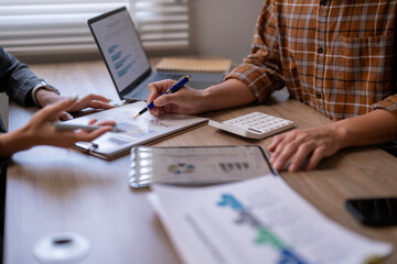 Two people are sitting at a table with a laptop, a notebook, a pen