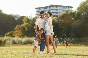 Obraz premium Closeness, embracing. Mother and father are with son outdoors on the field