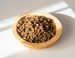 Dry pet food in sunlight, dog kibble pile, scattered puppy pellets, small canine protein croquette
