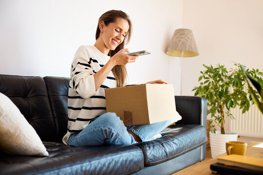 Woman at home preparing package shipment photographing with smartphone