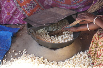 The close up of puffed rice making process on the heat pan by stirring with the broom