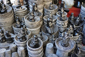 Multiple stone sculptures of Shiva Lingams which appear to be made of dark gray stone and feature the Om symbol