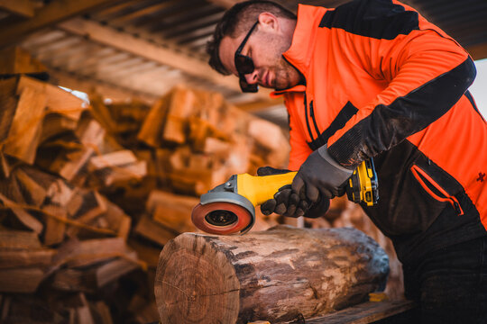 Man grinding with cordless wood grinder. Woodwork with aku grinder. Close up of grinder. Wood processing with angle grinder. Man dressed in reflective workwear.