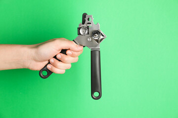 Woman holding can opener against green background, closeup