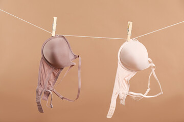 Beautiful bras hanging on rope against dark beige background