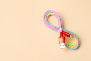 One USB charge cable on beige background, top view. Space for text