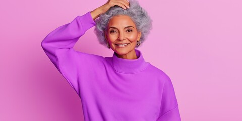 Fototapeta premium A woman with a purple sweater and gray hair is smiling. She is wearing earrings and a necklace