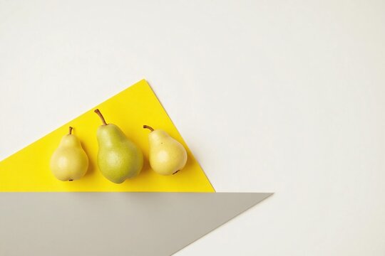 three pears triangular formation yellow grey surface white bg