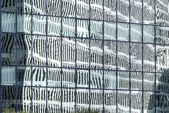 Distorted reflections of a cityscape on a glass-clad high-rise, creating an abstract urban pattern.