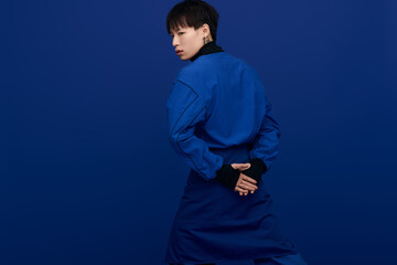 Young handsome man in stylish blue outfit poses confidently against a solid color background